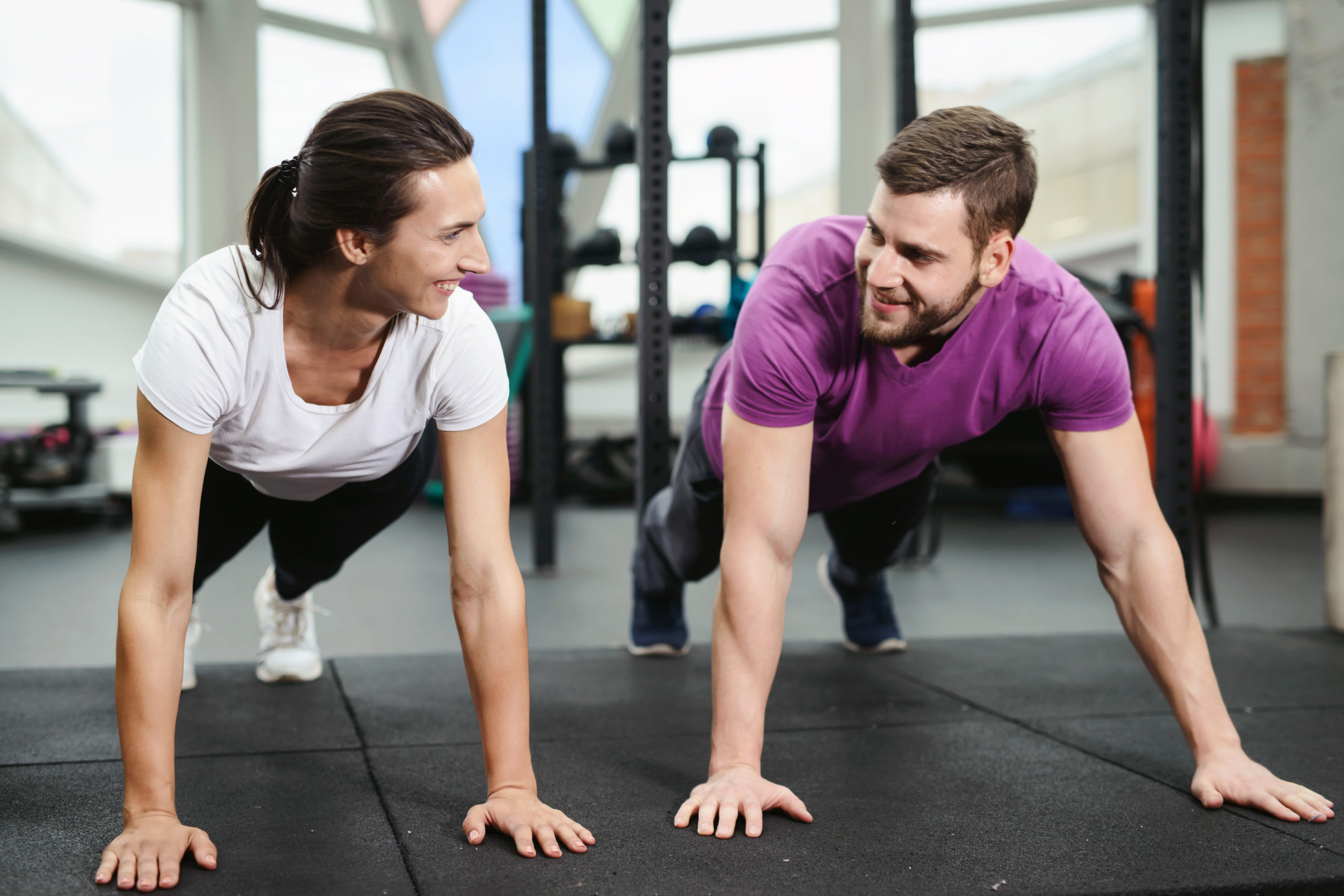Portrait of a muscular couple doing planking exercises in gym fitness health club. Together workout concept
